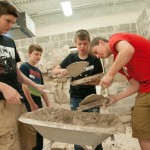 Students apply mortar to fabricated stone in the Construction Masonry Building.