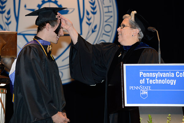 President Davie Jane Gilmour turns the tassel of student speaker Benjamin J. Schappell.