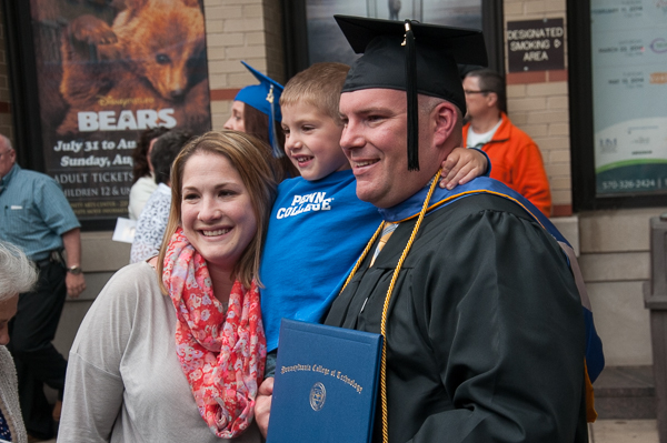 A grad poses with a young Penn College Proud fan.