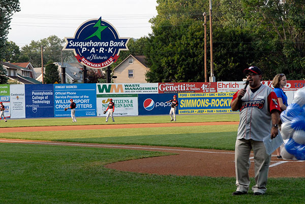 While Gabe Sinicropi, the Crosscutters' vice president of marketing and public relations, works the crowd, graphic design student Morgan N. Keyser, of Cogan Station, awaits the balloon launch and players warm up before Penn College's Centennial-themed panel on the outfield fence.
