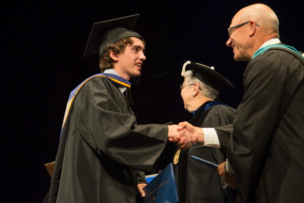A firm handshake cements a genuine occasion: a baccalaureate degree in web and interactive media for Brandon W. Knapp, of Pottsville.