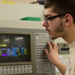 Manufacturing engineering technology student Andrew R. Klimek monitors a project on a piece of wire-cut electric discharge machining equipment.