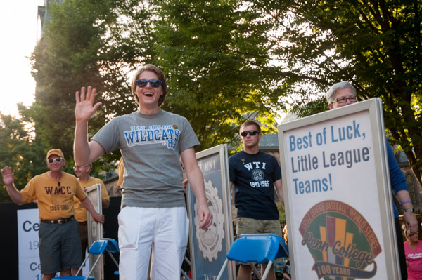 Alumni Raymond J. Fischer Jr., ’76 (left), and Nicholas D. Biddle, ’07 (foreground), wave to the crowds.