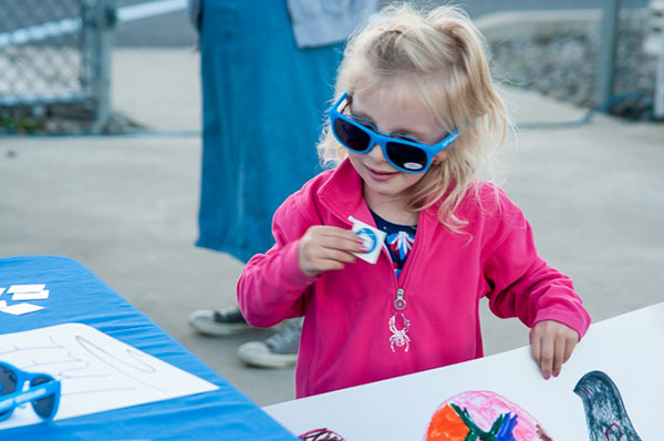 Pretty in pink (and Wildcat blue), a young fan dons her souvenir shades and grabs a logo 