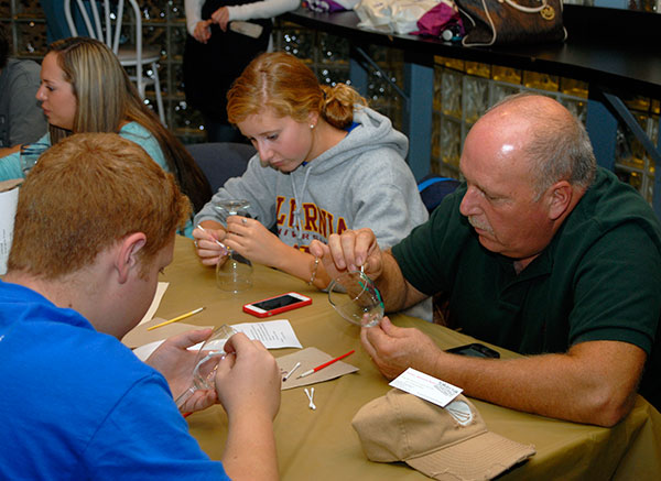 David W. DeRosato (foreground), of Norristown, majoring in building automation technology: electrical technology concentration, joins his sister, Marie, and his father, Bill, at the wine glass-painting activity in Penn's Inn.