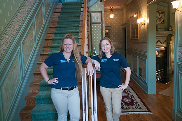 Welcoming guests for self-guided tours of the student-designed and -built Victorian House are Presidential Student Ambassadors Cassandra B. Mohr (left) and Morgan N. Keyser.