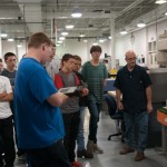Automated manufacturing technology student Bryce L. Kuszmaul (foreground, holding controller) demonstrates a robotic process.
