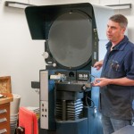 John G. Upcraft, instructor of machine tool technology/automated manufacturing, shows an optical comparator in the college’s metrology lab …