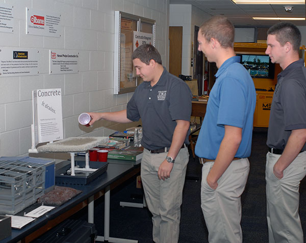 Construction management students (from left)  Matthew W. Bonenberger, of Lansdale; Charles J. Lutz, of Reading; and Ryan M. Huber, of Valencia, demonstrate the porousness of concrete.