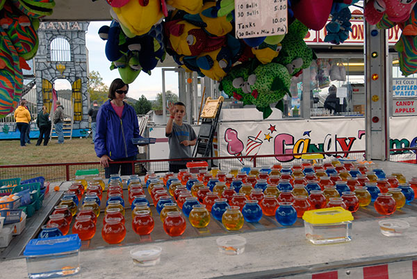 Exhibiting his fish-winning form along the carnival midway is Evan Miller, son of Tina M. Miller (left), director of marketing communications, and Ron Z. Miller,  director of computer services/portal development.