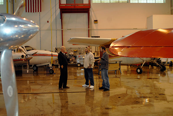 Standing amid the college's fleet of instructional aircraft are Walter V. Gower (left), an assistant professor of aviation, and a pair of Open House visitors.