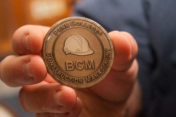 Baus shows off his coveted Construction Management Challenge Coin – a special memento of camaraderie among graduates of that major. 