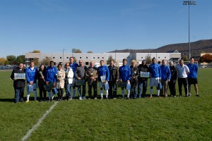 The blue-clad seniors on this year's Wildcat men's soccer team join their families and others. From left are Adrian Bukur, Blayne Allen, Evan Coyne, Christian Dressler, Jacob Tuck and Tristan Smith. Also pictured (from right) are team manager Jason Van Gent, coach Rafael Morais, President Gilmour and Kennell.