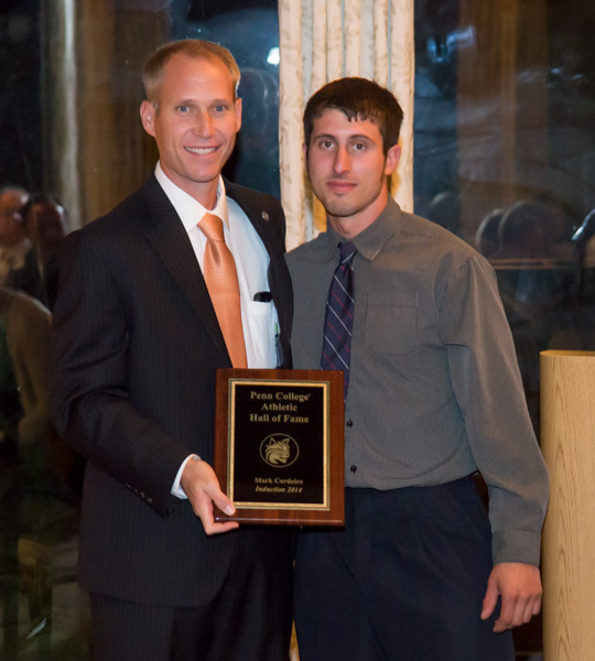 Athletic Director Scott Kennell presents a Hall of Fame plaque to cross-country standout Mark Cordeiro.
