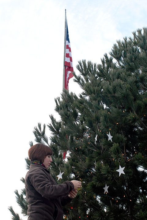 With fitting proximity to the towering American flag outside the Student and Administrative Services Center, admissions representative Sarah R. Shott strategically places a handful of ornaments.