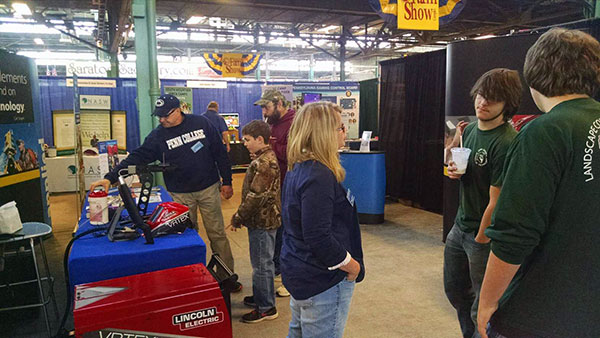 Welding instructor Timothy S. Turnbach and Stacey C. Hampton, assistant dean of industrial, computing and engineering technologies, engage an interested group of Farm Show attendees.