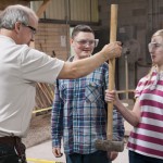 A middle-schooler feels the weight of a sledgehammer as Harry W. Hintz, instructor of construction technology, shows the group several tools of the concrete masonry trade, including …
