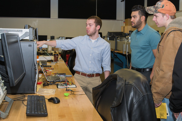 Hunter S. Forney (left) from Shippensburg, and Adrian I. Mundo, Selinsgrove, seniors in electronics and computer engineering technology, share their projects with a young guest. 