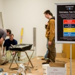 Construction continues alongside a sign explaining the Centennial commemoration.