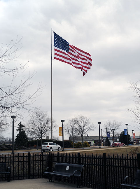 Frigid winds whip the large American flag at the campus entrance.
