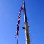 A worker is lifted aloft to unravel the Stars and Stripes.