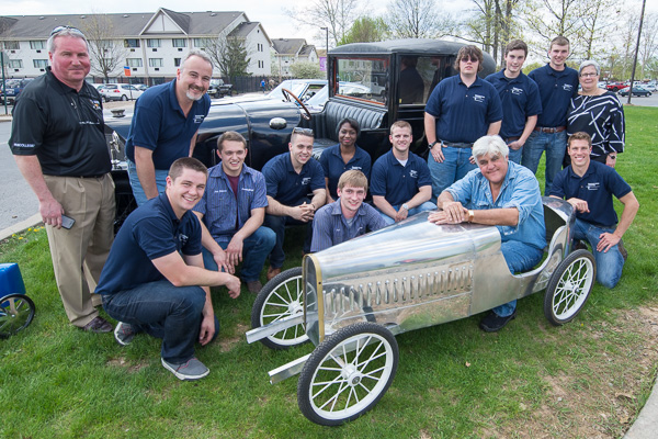 A group photo, with the guest of honor in a Bugatti, includes college President Davie Jane Gilmour (right) and Brett A. Reasner, dean of transportation and natural resources technologies (left).