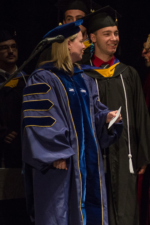 Maxwell A. Davert, graduating in building science and sustainable design, waits to be announced by Carolyn R. Strickland, vice president for enrollment management/associate provost. Davert, whose college years were marked by a series of well-received videos shot from a quadcopter, included the DJI logo and slogan on his mortarboard to acknowledge the drone's manufacturer. 