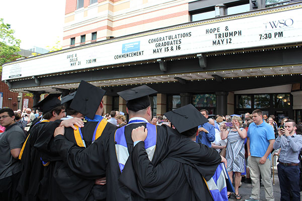 Graduates bond in front of their marquee mention.