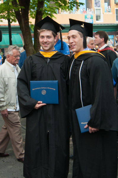 Two grads show off their diploma folders.