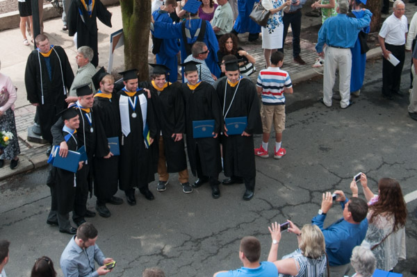 A lineup of smart-phone wielding photographers faces a lineup of new graduates.