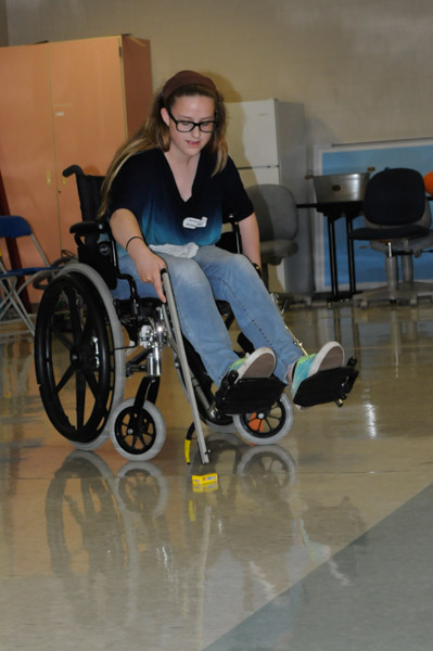 A Jersey Shore Area Middle School student uses a “grabber” to pick up a box of candy as part of a wheelchair challenge.