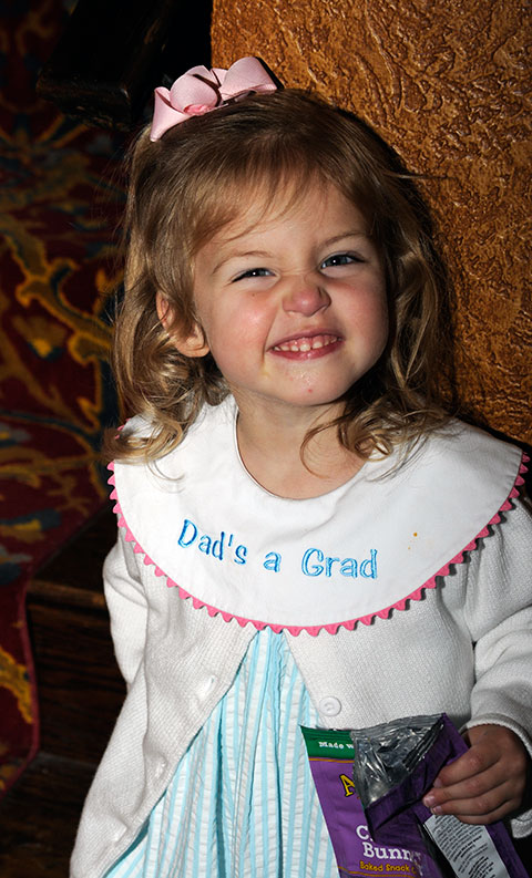 The 3-year-old daughter of Benjamin A. Hess (accompanied off-camera by her mother, Stephanie) is proudly in Dad's corner on graduation day. Hess, a 2003 Alumnus Achievement Award winner, added a bachelor's in technology management to his 1995 associate degree in computer aided drafting and design. 