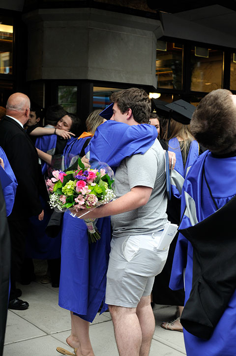 As rain coincides with Friday's recessional, grads hug their well-wishers under the CAC marquee.
