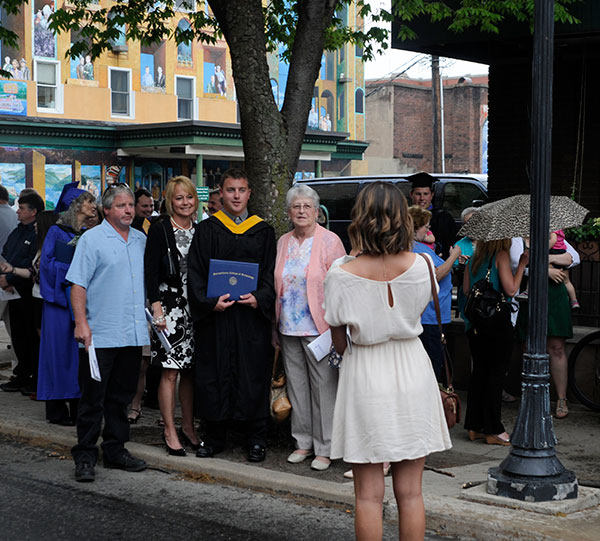 Crossing the street to escape the crowd and finding a natural canopy to deflect raindrops, a family creates a photo op.