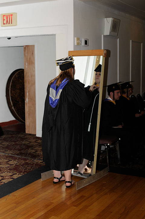 As the clock ticks toward Friday's procession, culinary arts and systems major Briana R. Helmick, of Hershey, makes one last assessment in a Genetti Hotel mirror.