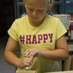 A happy camper rolls out clay in the college ceramics room. 