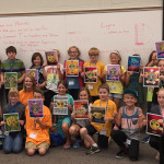 Campers pose on their final day and show off the masks they created in Photoshop. One of their mentors, Ainsley R. Bennett, a junior in graphic design, can be seen in the second row. (Photo by Penny Griffin Lutz)