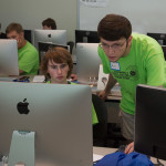 Matthew A. Bamonte (right) who graduated last month with a bachelor's degree in information technology sciences-gaming and simulation, assists a young camper with his question.