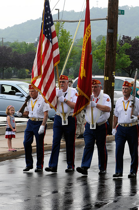 Appropriately attired in red, white and blue, a young parade-goer stands at attention for the passing color guard.