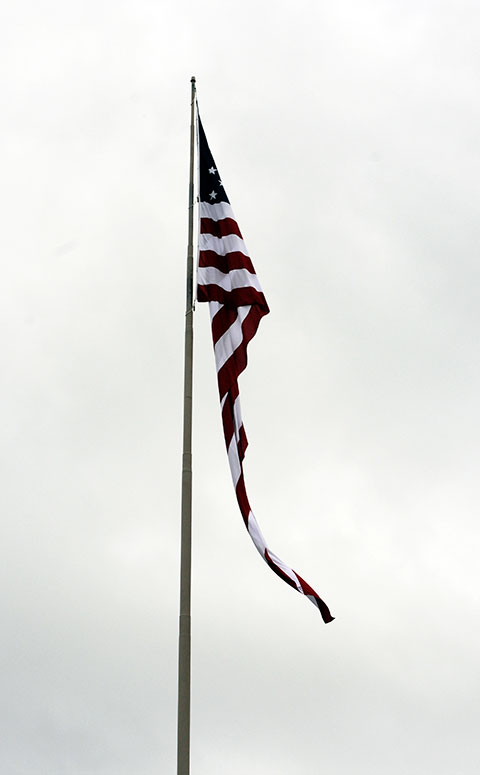 The college's 1,800-square-foot flag, which minutes before languished in the sticky and stagnant air, begins to flutter during a nationally simultaneous Pledge of Allegiance at the stroke of 7 p.m.