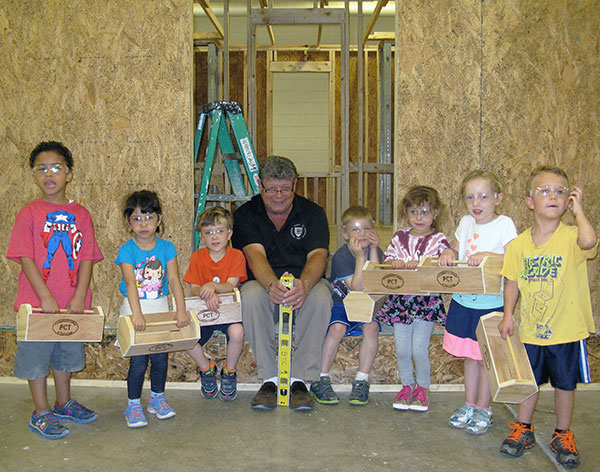 The dean happily sits for a wrapup photo with Monday's first wave of carpentry kids.