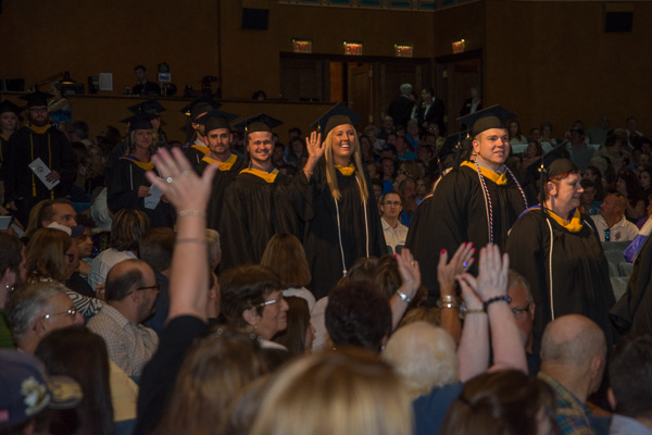 A graduate waves to her fans as the Class of ‘15 files into the Community Arts Center.