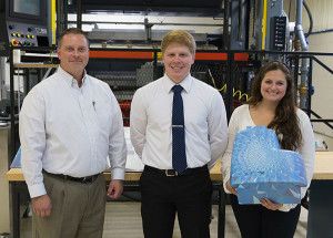 Plastics and polymer engineering technology majors Jacob W. Fry and Madison T. Powell hold one of the parts they made for a recent competition at the Society of Plastics Engineers Thermoforming Conference in Atlanta. Christopher J. Gagliano (far left), program manager for the Thermoforming Center of Excellence at Penn College’s Plastics Innovation & Resource Center, supervised the student project. 