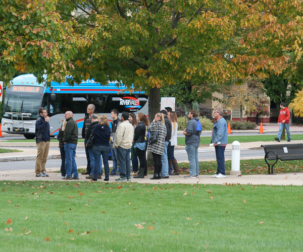 Josiah D. Stoltzfus, a Presidential Student Ambassador and a Community Assistant, leads a pack of eager visitors on a walking tour (as a shuttle bus departs from the Bush Campus Center).
