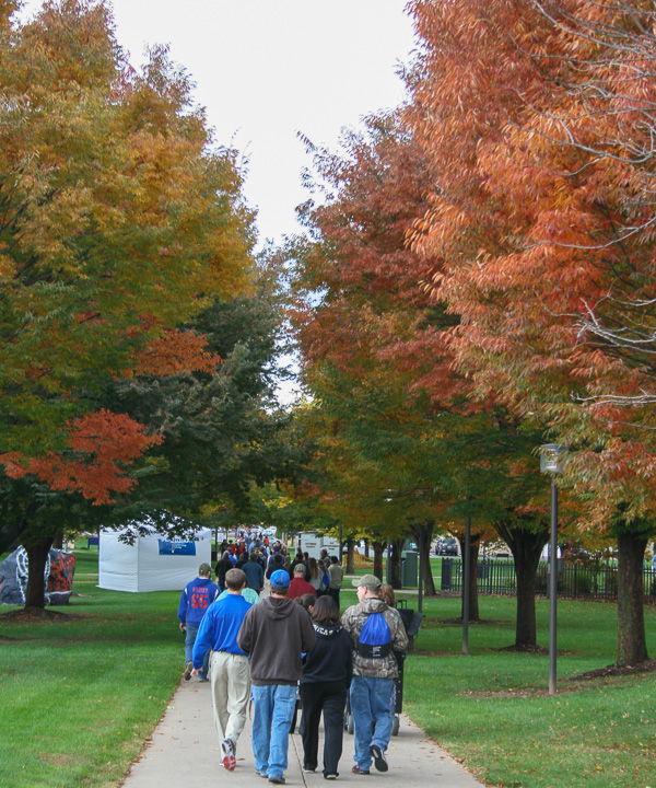 A campus mall sidewalk teems with visitors as far as the eye can see (or feet can walk). 