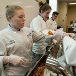 Alivia L. Bollock joins Classical Cuisines of the World classmates in plating bacon samples they prepared earlier.