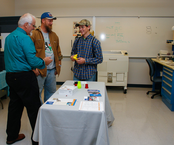 A father and son -  both interested in their educational options - learn about additive manufacturing from Dave A. Probst (left), assistant professor of engineering design technology.