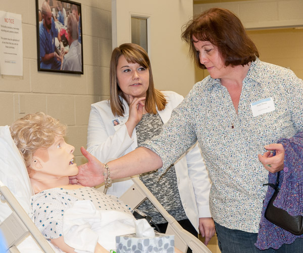 Hope Shoop, who graduated from WACC’s licensed practical nursing program in 1980, checks the pulse on SimMan with nursing student Haylea D. Estright, of Brisbin, who was one of the day’s tour guides.