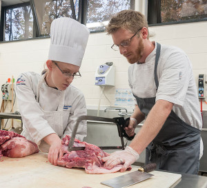 Chef Lance Smith, executive chef of The Millworks in Harrisburg and a 2006 Pennsylvania College of Technology graduate, returned to the college to guide culinary arts students, including Dallas A. Tyree, of Stillwater, left, in butchering hogs and making hams, bratwursts and other products.