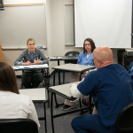 Students representing various majors talk through a patient’s case with Tushanna M. Habalar, instructor of nursing (in gray sweater).
